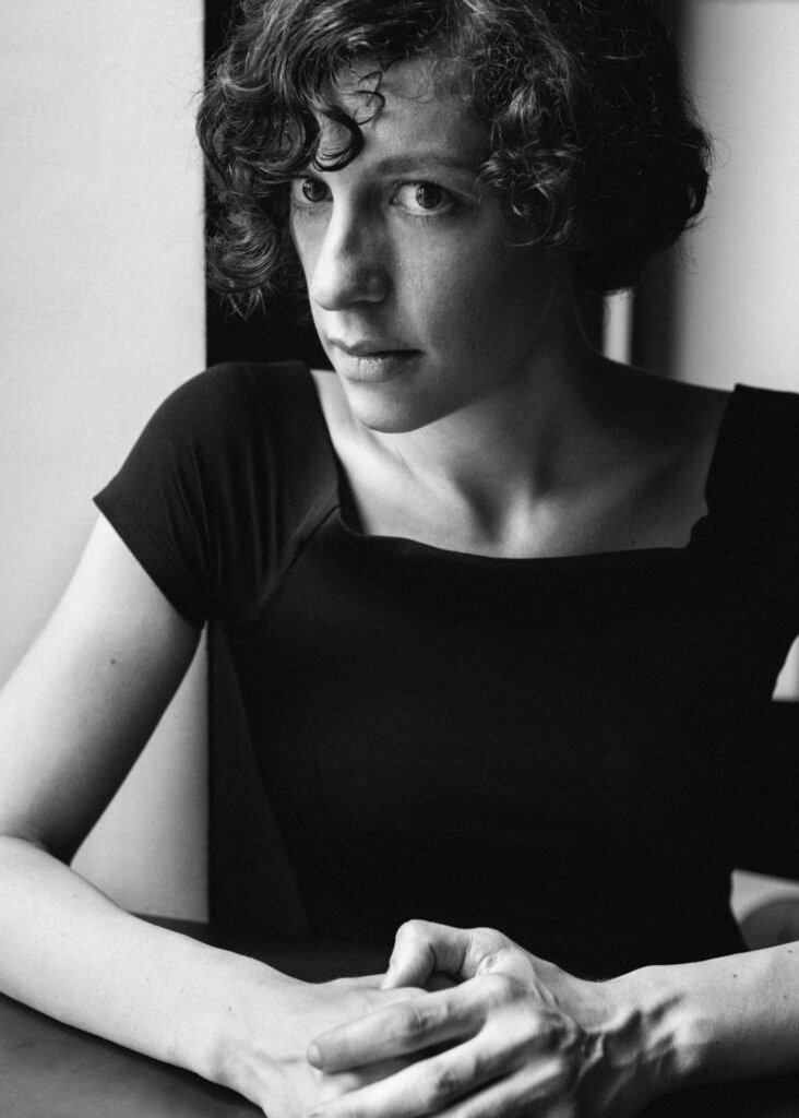 A monochrome portrait of a woman with curly hair and an introspective gaze, embodying 'mono no aware' through the ephemeral beauty of human expression and the impermanence of time.