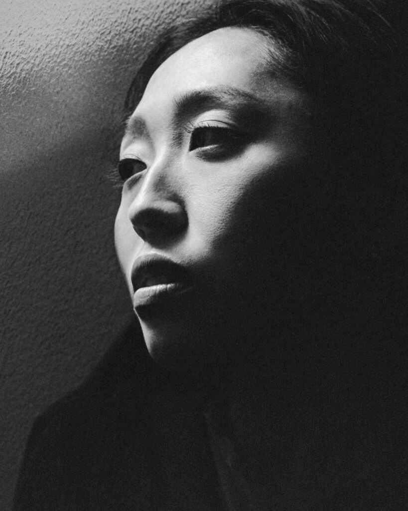 Close-up portrait of a Japanese woman in black and white, reflecting a contemplative mood that captures the essence of mono no aware and the ephemeral quality of human emotions.