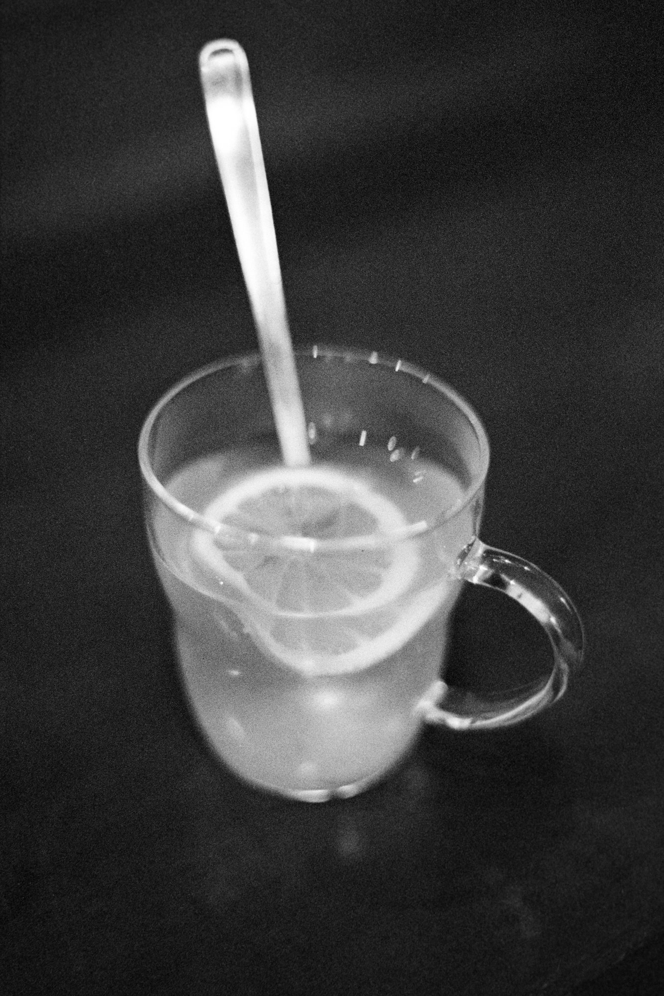 Black and white diptych of a full and empty glass cup of lemon tea, with a spoon resting inside. This image captures the ephemeral beauty of a warm drink, evoking the concept of mono no aware and the impermanence of simple moments.